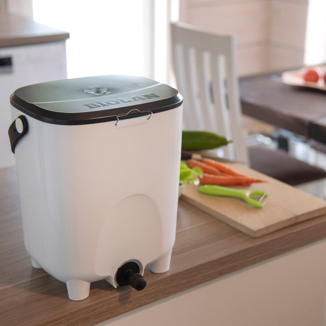 White kitchen Bokashi bin with black lid on a wooden countertop, featuring the brand 'BIOLAN'.